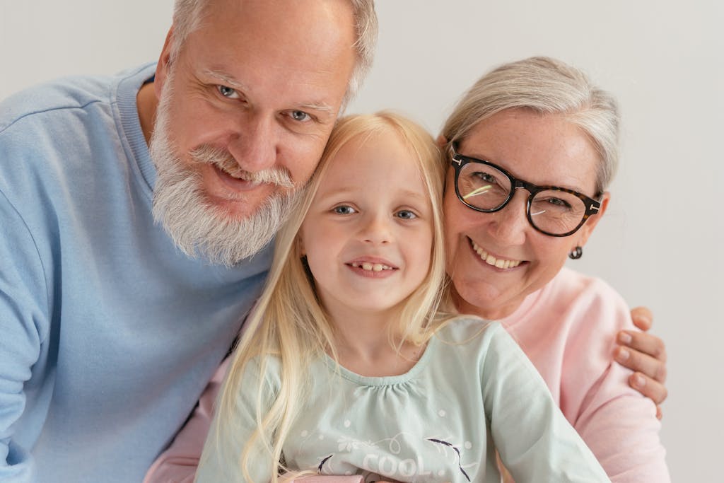 Happy grandparents and their grandchild smiling together indoors, showcasing family love and togetherness.
